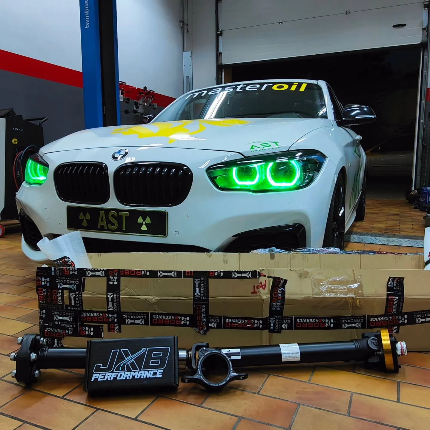 Weißer BMW M140i mit Angel Eyes in der Werkstatt vor dem AST-Performance-Banner